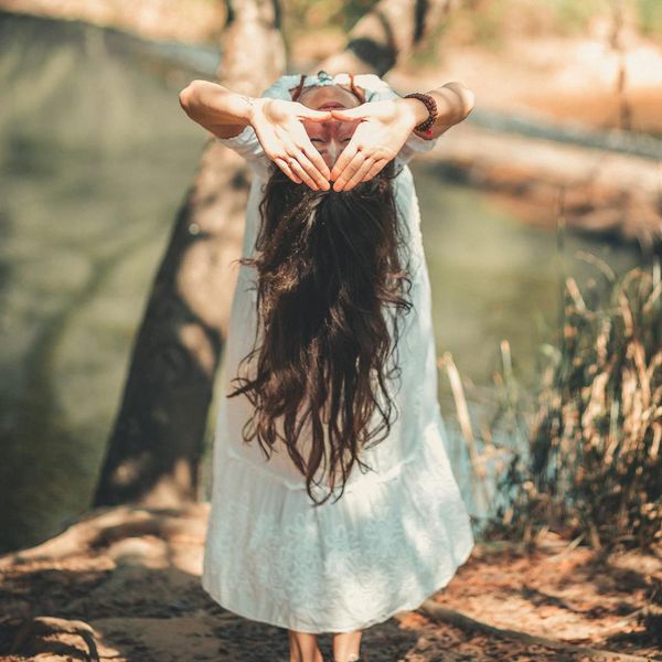 Person meditating peacefully in a calm, natural setting by the water.